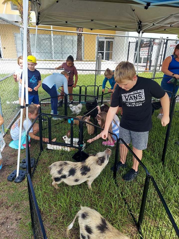 Summer camp kids enjoying a visit from our petting zoo animals for an in-house field trip in Jacksonville, Florida.